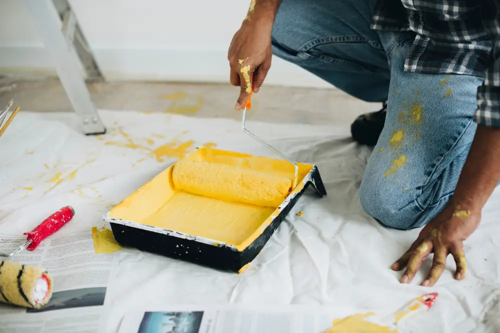 man painting walls yellow